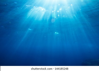 Underwater shot with sunrays and fishes in deep tropical sea - Shutterstock ID 144185248