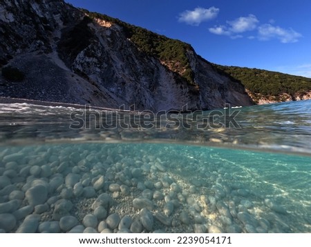 Underwater split photo of famous paradise pebble beach of Myrtos one of the best in island of Kefalonia, Ionian, Greece