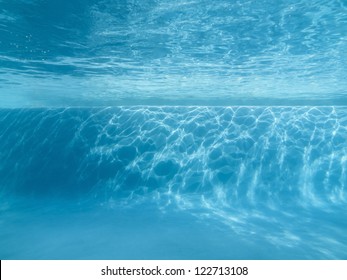 Underwater swimming pool ledge with sunlight patterns.
