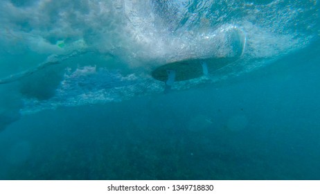 UNDERWATER: Unrecognizable Surfer Riding The Glassy Ocean Waves On A New White Surfboard. White Surfboard Gliding And Carving Through Turquoise Sea Water And Making Ripples As It Passes The Camera.