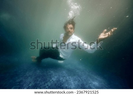 Underwater view of frustrated lonely male sinking in deep water of swimming pool