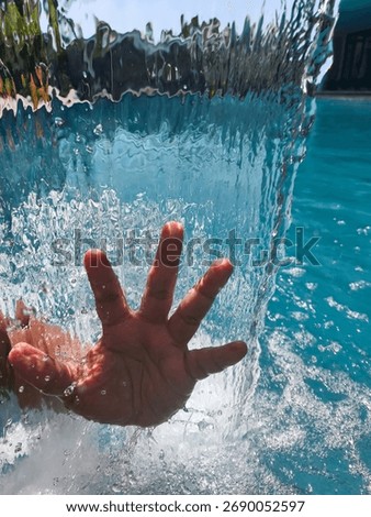 Underwater view of a hand reaching for the surface amidst bubbles and light.