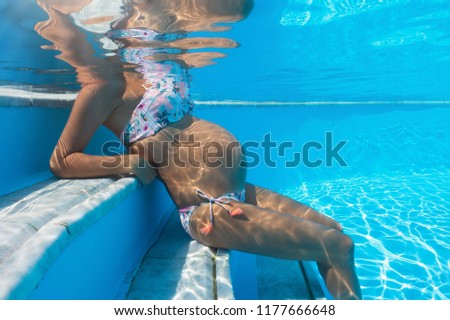 Underwater view of a pregnant woman sitting in the swimming pool