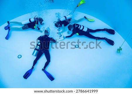 Underwater view of a scuba diving instructor and students assembling a puzzle on the pool floor