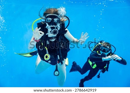 Underwater view of a scuba diving instructor and a teenage girl student training in a deep swimming pool