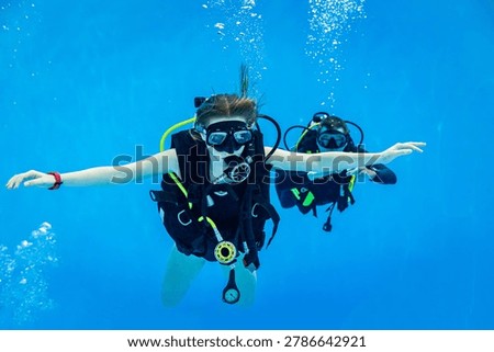 Underwater view of a scuba diving instructor and a teenage girl student training in a deep swimming pool