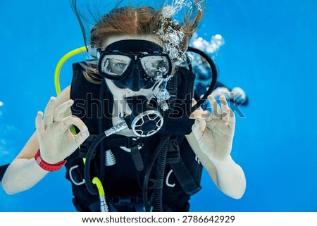 Underwater view of a scuba diving instructor and a teenage girl student training in a deep swimming pool