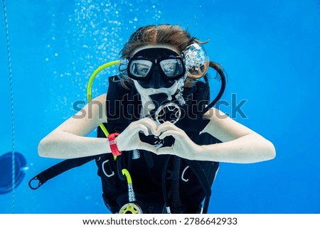 Underwater view of a scuba diving instructor and a teenage girl student training in a deep swimming pool