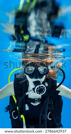 Underwater view of a scuba diving instructor and a teenage girl student training in a deep swimming pool
