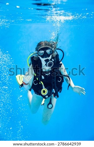 Underwater view of a scuba diving instructor and a teenage girl student training in a deep swimming pool