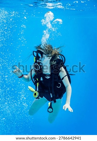 Underwater view of a scuba diving instructor and a teenage girl student training in a deep swimming pool
