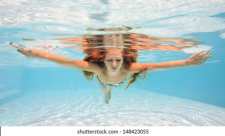 Underwater woman portrait wearing bikini in swimming pool. 