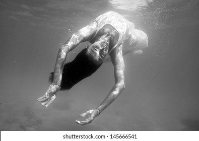 Underwater Woman Portrait With White Dress Into The Sea. Black And White Image. 