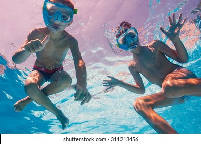 Underwater Young Brothers Kids In Swimming Pool With Mask.