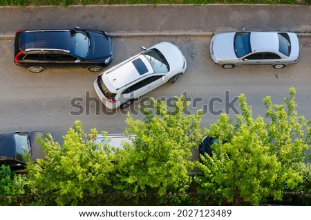 The uneasy parking of the white car near black and grey, shot from above