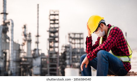 Unemployed concept from coronavirus or covid 19 crisis. Engineer asian man wearing yellow safety helmet, goggle and face mask sitting sad outside factory because of his lay-off. Unemployment crisis. - Powered by Shutterstock