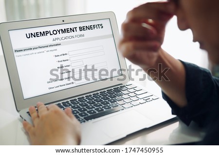 Unemployed depressed person filling out an online unemployment benefits application form using laptop computer.