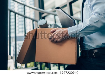 Unemployed hold cardboard box and laptop bag, dossier and drawing tube in box. Quitting a job, businessman fired or leave a job concept. Foto d'archivio © 