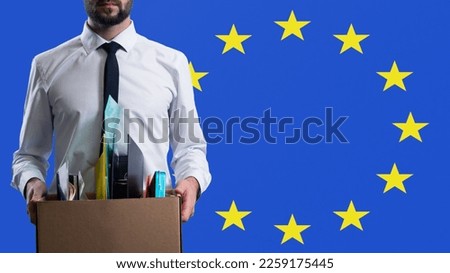 Unemployed man. European Union flag behind guy. Dismissed man With cardboard box. Unemployment in European countries. Mass layoffs in European Union. Dismissed office worker. Labor market crisis