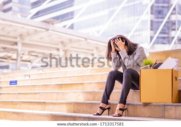 Unemployed stressed office people\
sitting outside office with her box of office\
properties.