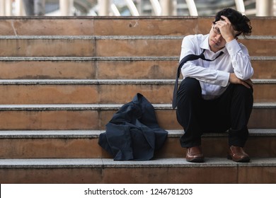 Unemployed stressed young Asian business man in suit covering face with hands. Failure and layoff concept. - Shutterstock ID 1246781203