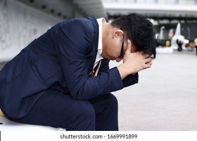 Unemployed stressed young Asian business man suffering from severe depression. Failure and layoff concept.