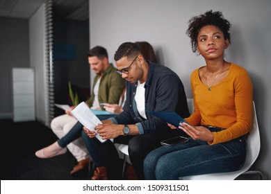 Unemployed Young African American Woman Feeling Stressed About Tedious Waiting Sitting In Queue With Other Candidates For Job Interview