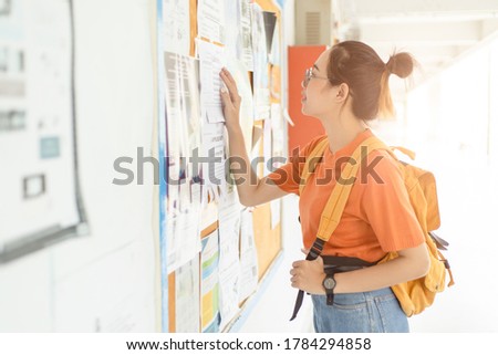 Unemployed young university woman looking for work or job after graduation at the post board