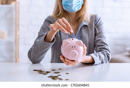 Unemployment During Coronavirus Epidemic. Woman In Mask Puts Coins Into Piggy Bank