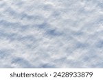 Uneven lumpy close up snow surface. Pressed snow melted in the sun. White and blue texture or abstract winter background
