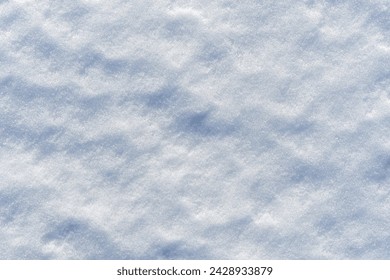 Uneven lumpy close up snow surface. Pressed snow melted in the sun. White and blue texture or abstract winter background