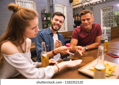 Unfair. Beautiful young girl looking upset while playing games in the bar with friends