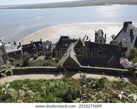 Unfiltered, original, summer, blue sky photograph of Mont Saint-Michel, Abbaye du Mont Saint Michel, the must see tourist destination in Normandy, France. Bucket list abbey, iconic abbey and village.