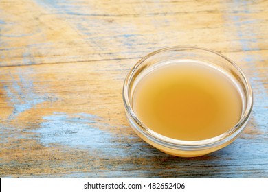 unfiltered, raw apple cider vinegar with mother  - a small galls bowl against wood with a copy space