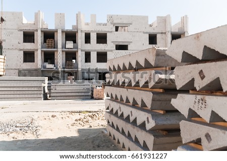 Unfinished apartment building of autoclaved aerated concrete block. In the foreground stacked concrete plank and Concrete staircases