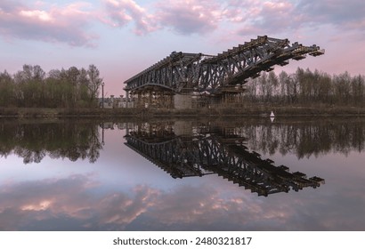 An unfinished bridge over calm water reflects the twilight sky, creating a serene, symmetrical landscape. - Powered by Shutterstock