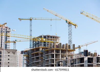 unfinished building construction and building cranes against clear blue sky background