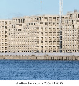 Unfinished concrete building under construction near a water body. Architectural development and urban infrastructure concept. - Powered by Shutterstock