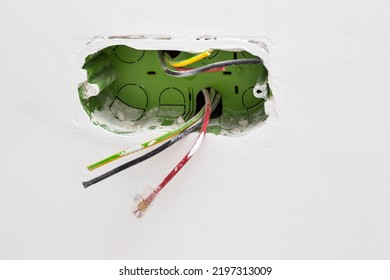Unfinished electrical mains outlet socket with electrical wires - connector installed in plasterboard drywall for gypsum walls in apartment is under construction and remodeling.