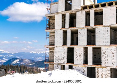 Unfinished house,building,hotel,mansion construction in winter snow forest in mountains,nature panorama.Ski alpine resort,travel.Calm countryside. Home residence in coniferous spruce pine trees