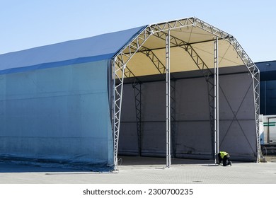 Unfinished large prefabricated arched metal frame tent hangar covered with gray polyvinyl chloride fabric