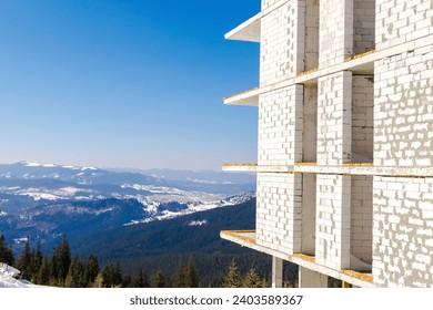 Unfinished multi-storey house,building,real estate,hotel,mansion construction in winter snow mountains,nature panorama.Ski alpine resort,travel.Calm countryside. Home residence.
