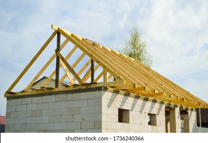unfinished roof construction of a small house - a wooden frame of the roof, rafters and beams - Shutterstock ID 1736240366