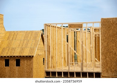 Unfinished roofing with OSB Oriented Strand Board plywood sheathing near timber frame house wooden posts beams under construction suburbs Atlanta, Georgia, USA. Suburban American residential building - Shutterstock ID 2358736959