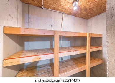 Unfinished Small Storage Room With Concrete Walls And Wooden Shelves