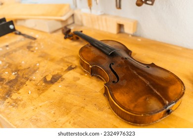 Unfinished violin placed on wooden table in workshop - Powered by Shutterstock