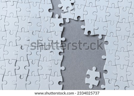 Unfinished White Puzzle with Copy Space Isolated on paper Background. Pieces of jigsaw puzzle on background.

