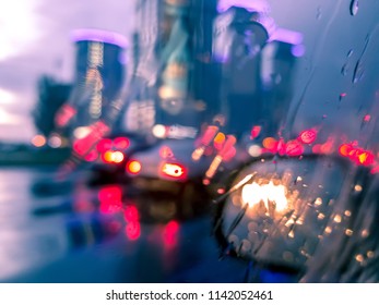 Unfocused Background Of Modern City Street View Under The Rain From The Driver Seat Of The Car.