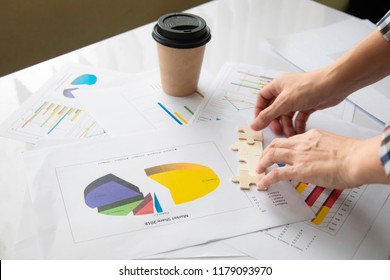 Unfocused business woman hands start up the jigzaw puzzles on statistic graph financial paper background with copy space/ stretegic business start up concept