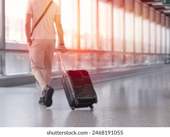 Unfocused photo of unrecognizable man walking with suitcase in airport terminal - Powered by Shutterstock